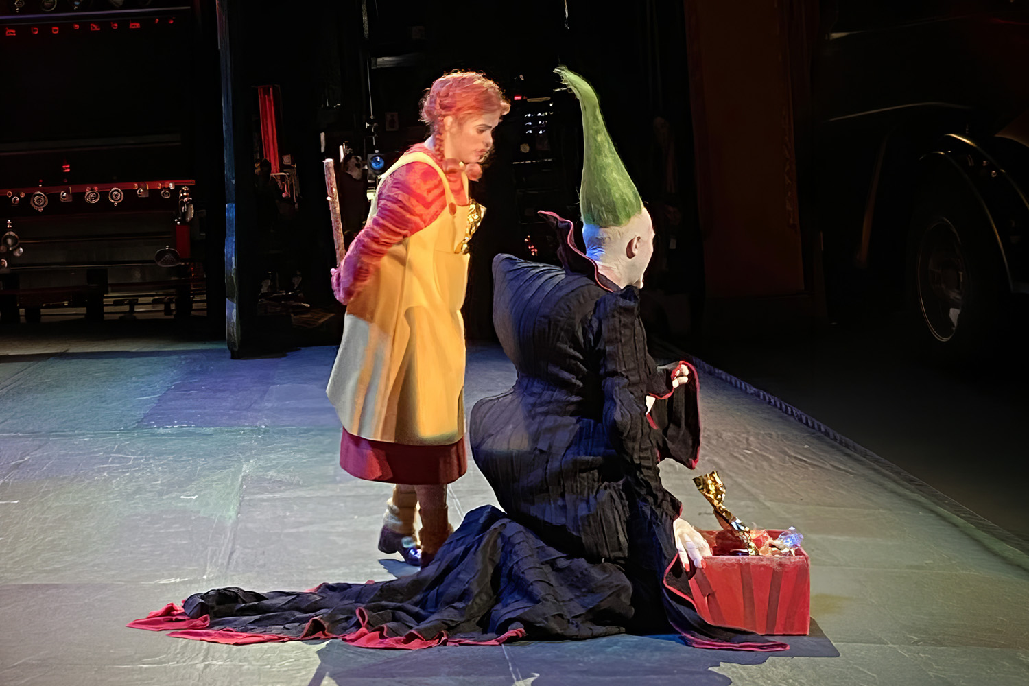 Costumed performers in character, including a yellow dress and a green hat with a gift box