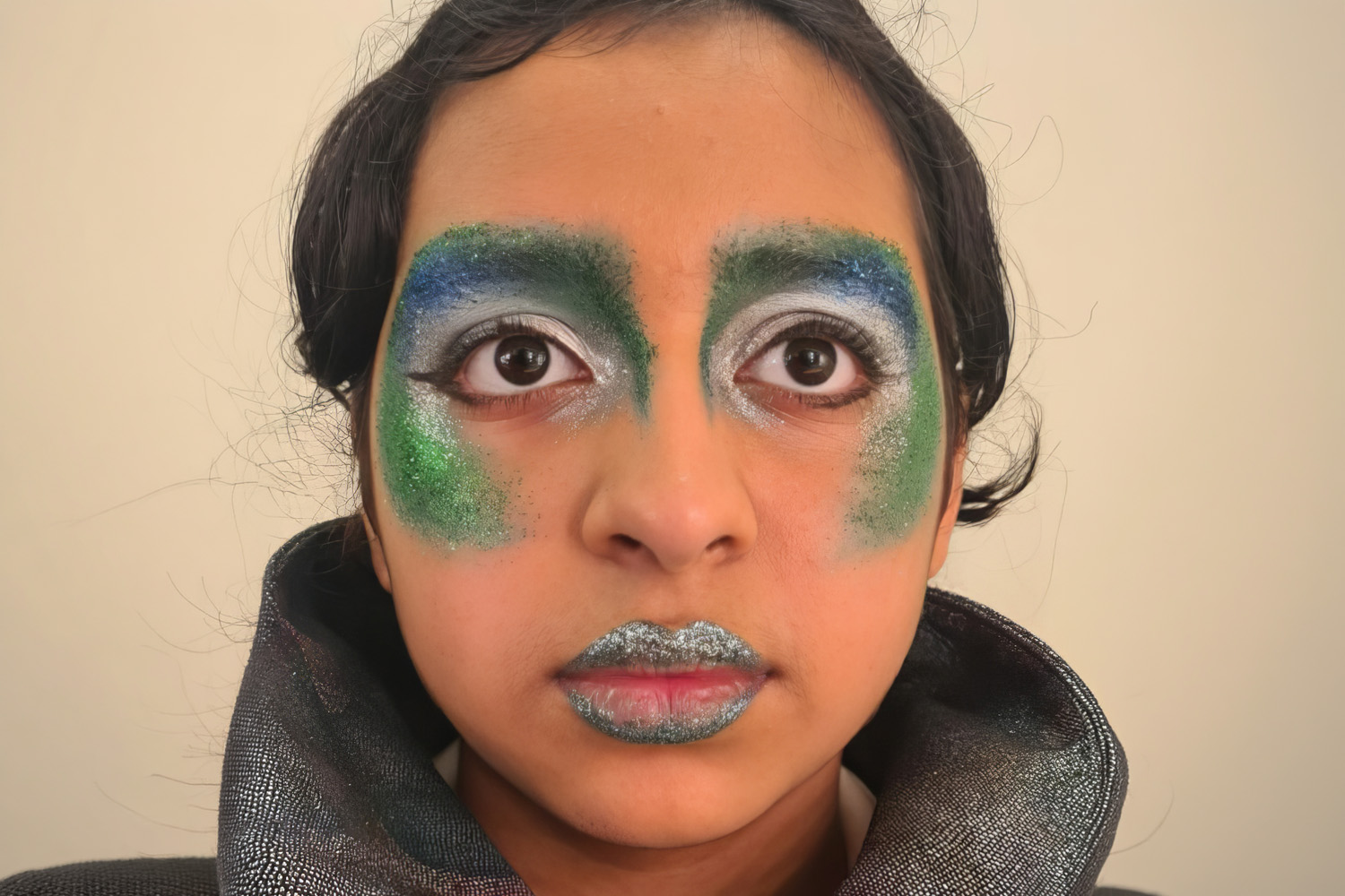 Close-up of theatrical makeup in green and blue glitter tones