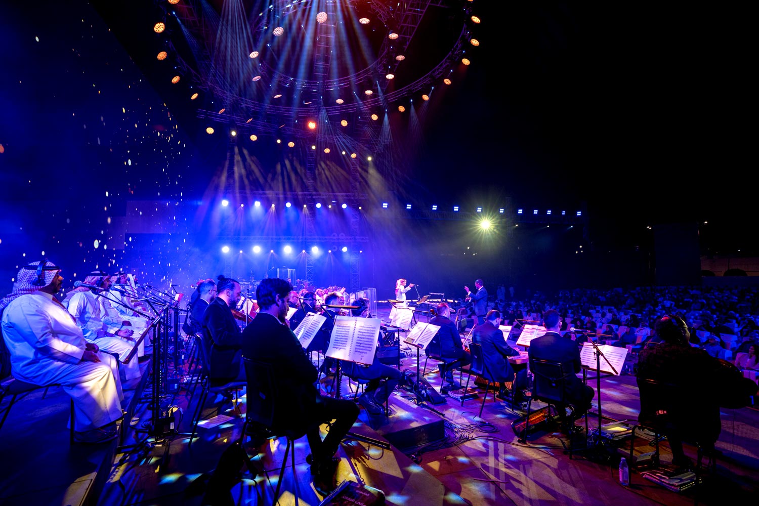 Wide view of outdoor concert with orchestra under the lighting rig