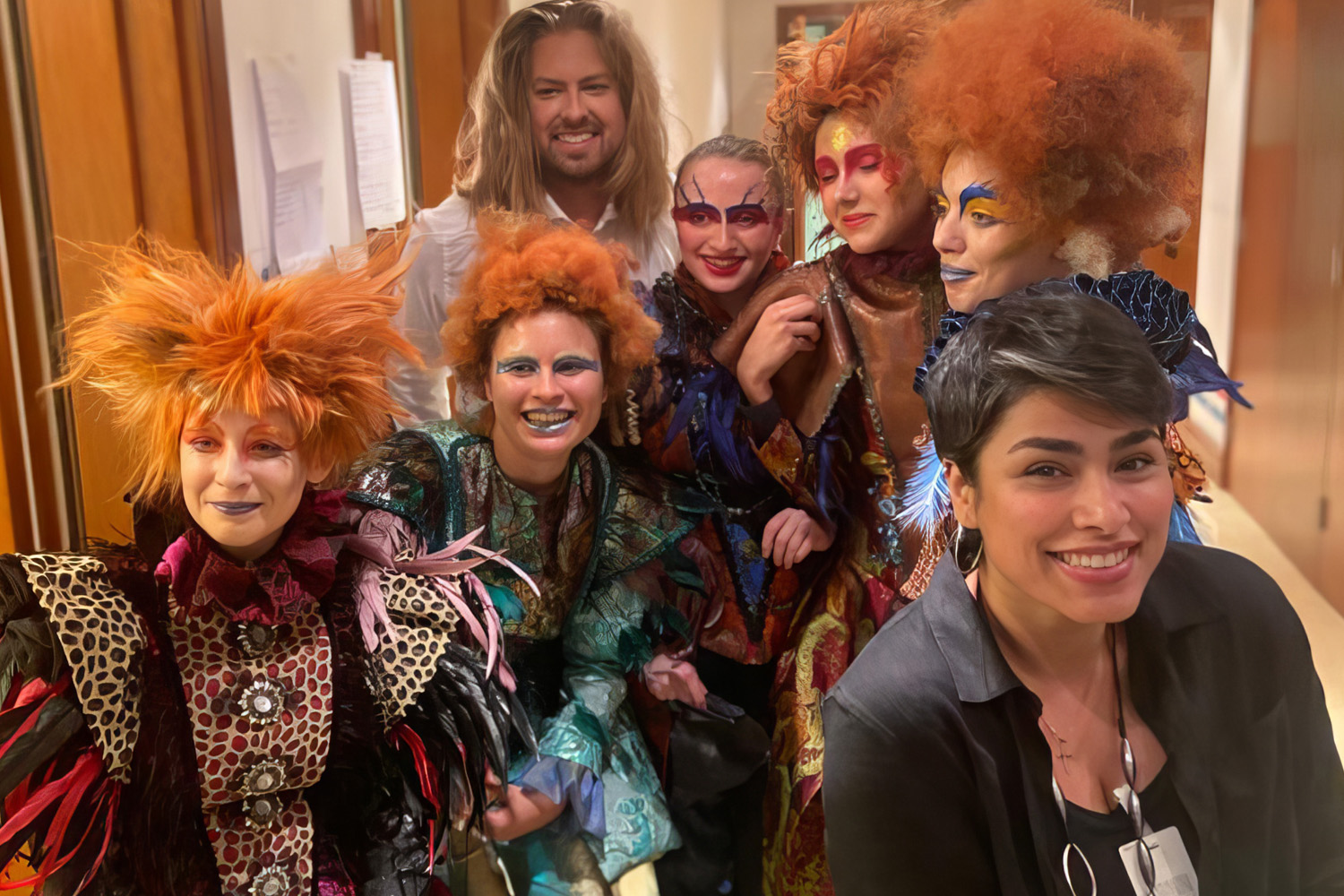 Performers in orange wigs with colourful stage makeup