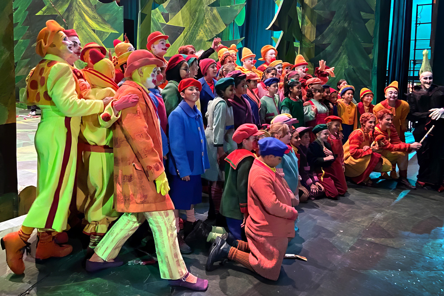 Full chorus in costume on stage against a forest backdrop